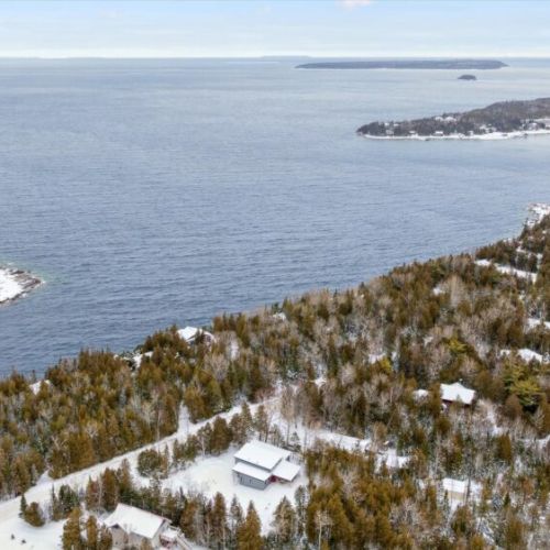 Aerial water views overlooking rugged shoreline, forested land, and expansive blue horizons.