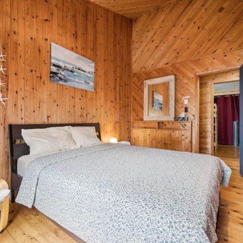 Cozy main-floor bedroom featuring a comfortable queen bed and warm pine interiors for a relaxing night's sleep.