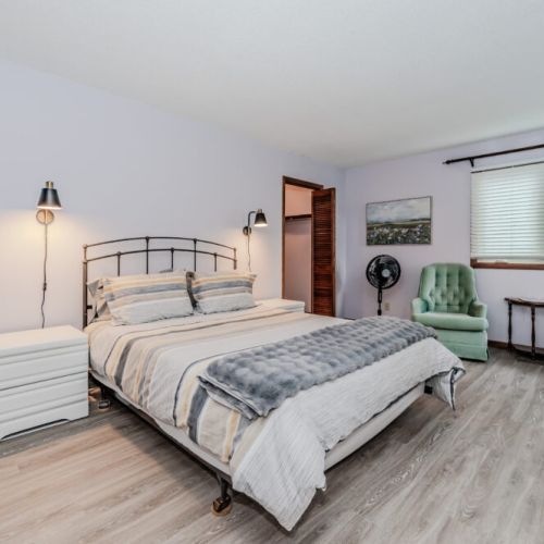 Bright master bedroom with modern decor, offering peaceful lake views and a cozy retreat for your vacation stay.