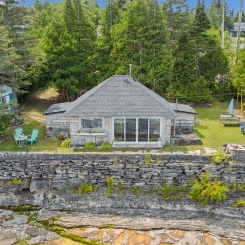 Stone wall and large windows frame the cottage beautifully.