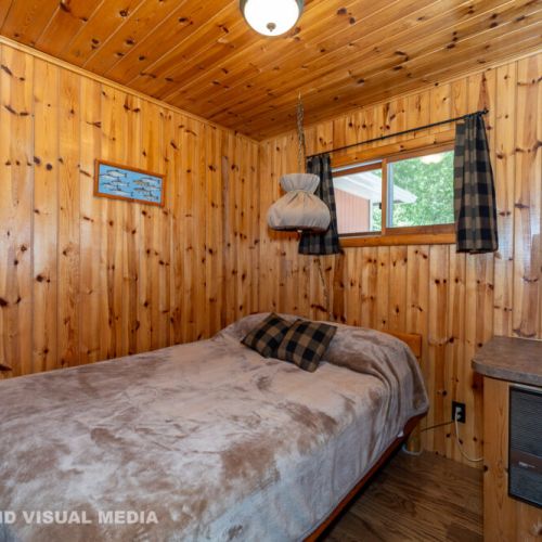 A warm, wood-paneled bedroom with a comfortable double bed—perfect for quiet, restful nights.