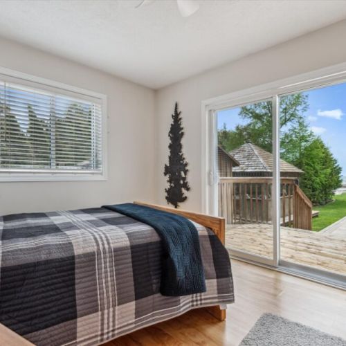 Second bedroom with lakefront walk-out – A cozy lakeside retreat offering direct access to the wraparound deck.