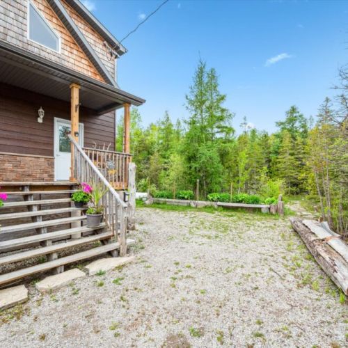 Step up to the warm and welcoming front porch adorned with colorful potted flowers and wood siding. It’s the perfect blend of country comfort and serene living.