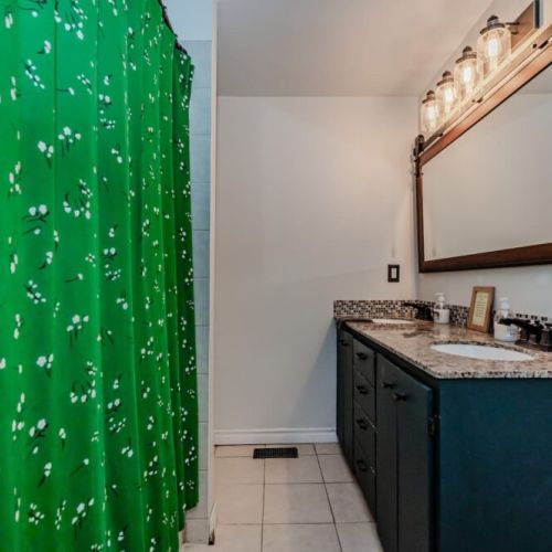 Main floor bathroom with dual entryways, full vanity, and a bright pop of color. Convenient for guests in both wings of the cottage.