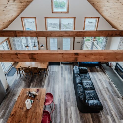 A stunning view of the great room from the loft, showcasing the open floor plan, high ceilings, and the cozy living and dining areas.