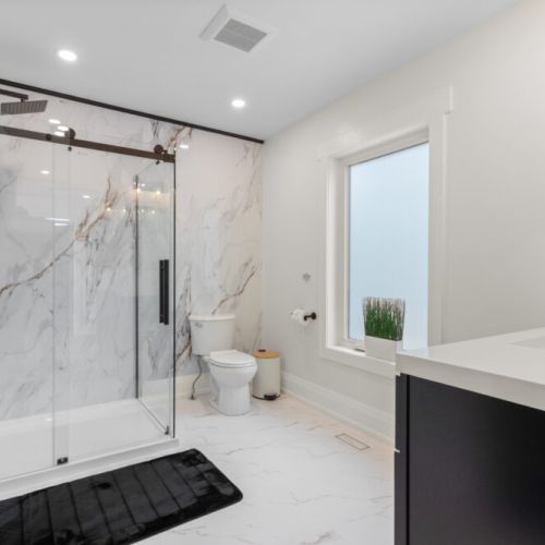 The spacious bathroom features a walk-in glass shower and modern finishes.