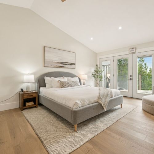 Unwind in a spacious king suite with vaulted ceilings, walk-out deck access, and natural textures for a boutique-hotel feel.