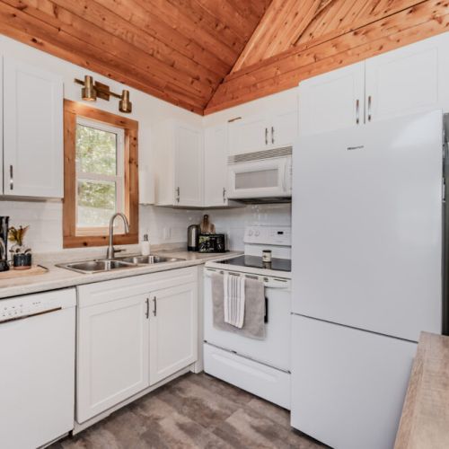 Fully equipped modern kitchen featuring white cabinetry, updated appliances, and all essentials for an easy and relaxing cottage vacation.
