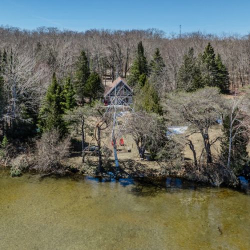 Peaceful lakefront cottage escape surrounded by lush trees. Enjoy direct access to the crystal-clear water for swimming, kayaking, and lakeside relaxation!