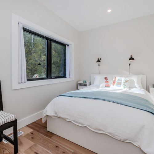 Wake up to tranquil forest views in this charming, sunlit bedroom with modern finishes and inviting decor, ideal for a peaceful vacation escape.