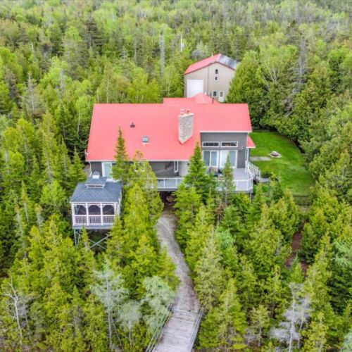 Tucked into the evergreens, the home’s elevated hot tub pavilion and wraparound deck blend seamlessly with nature. The forest provides not only privacy but peace, ideal for every season.