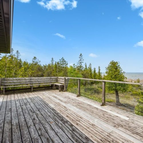 Unwind on the expansive upper deck with glass railings and built-in seating, offering panoramic views of Dorcas Bay — the perfect place to catch a sunset.