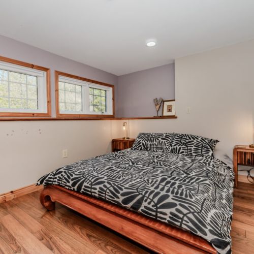 Relax in this inviting guest room with a queen bed, nature-facing windows, and calming tones—ideal for couples or solo travelers seeking a quiet escape.