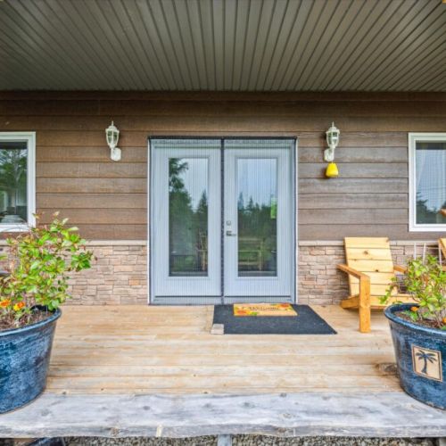 Step up to the warm and welcoming front porch adorned with colorful potted flowers and wood siding. It’s the perfect blend of country comfort and serene living.