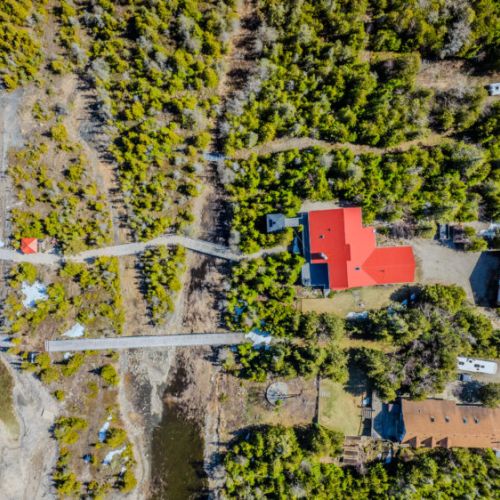 From the top-down, the property layout shines: expansive home, garage with solar panels, and a long winding boardwalk leading directly to your private 100-ft dock. Boaters, this is your dream come true.