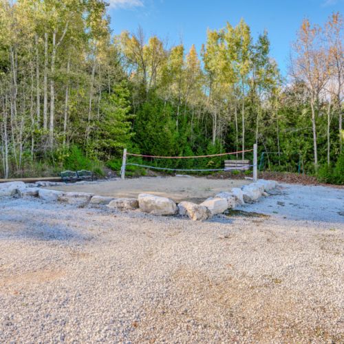 Well-maintained sand volleyball court surrounded by trees, providing a fun activity for guests to enjoy together.