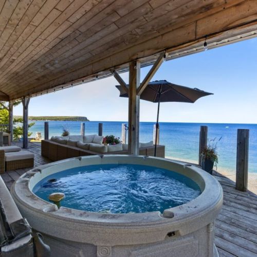A luxurious outdoor deck featuring a private hot tub and comfortable lounge seating, all while enjoying breathtaking views of Georgian Bay.