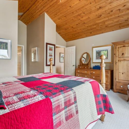 Primary bedroom retreat with vaulted ceiling, rustic furnishings, and cozy charm for restful nights.