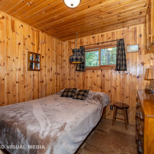 Warm, cabin-style bedroom with wood paneling and plush bedding for a peaceful night’s rest.
