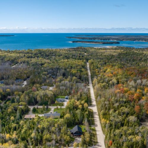 Enjoy the breathtaking aerial view of the surrounding area, nestled between lush forests and a serene body of water.