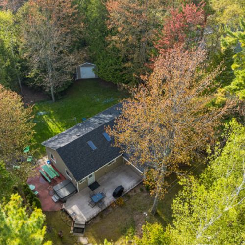 An aerial view showcases the expansive yard, outdoor living spaces, and secluded natural surroundings.