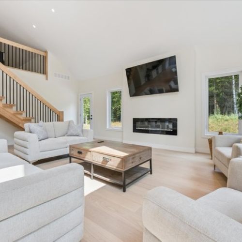Stylish and sunlit, this open living space showcases vaulted ceilings, a sleek electric fireplace, and a cozy layout ideal for gathering with family and friends.