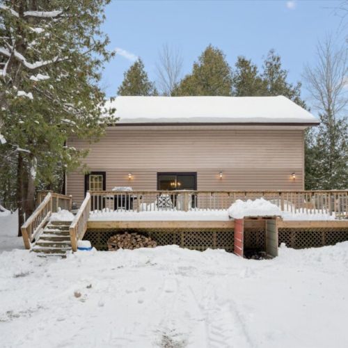 Expansive rear deck surrounded by trees, offering privacy and year-round outdoor enjoyment