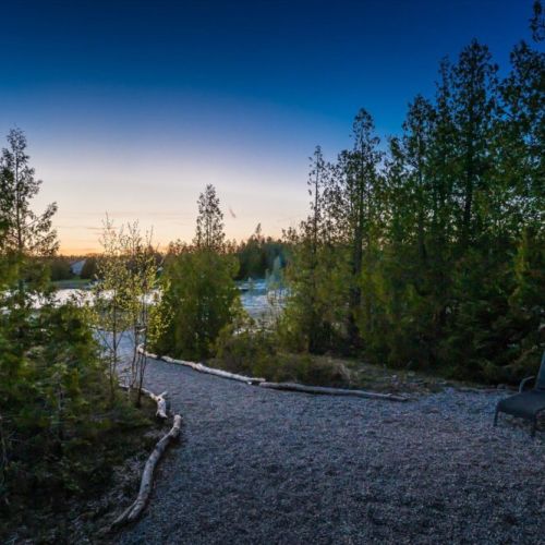 A peaceful gravel pathway leads you through the trees toward the water’s edge.