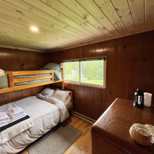 Cozy bedroom setup with bunk beds and a bright window, perfect for kids and friends, featuring fresh laundered linens and wooden charm.