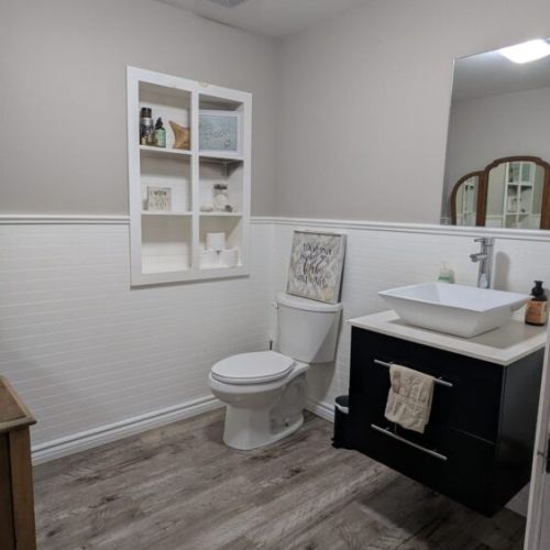 Modern full bathroom with stylish vanity, shelving, and plenty of space for guests.