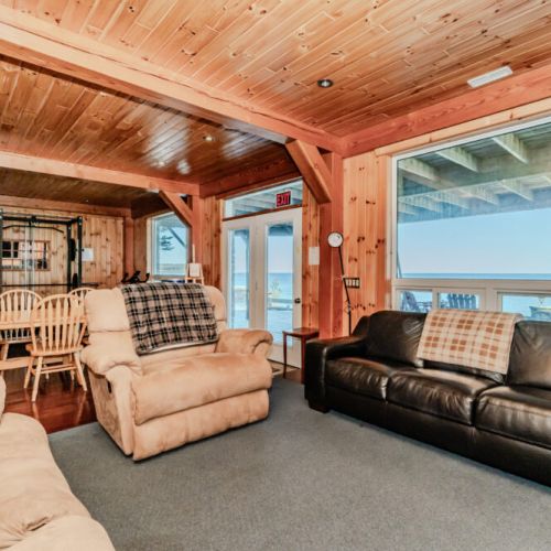 Cozy cabin-style living room with plush seating, lake views, and open-concept dining—ideal for family vacations, group retreats, and lakeside lounging.