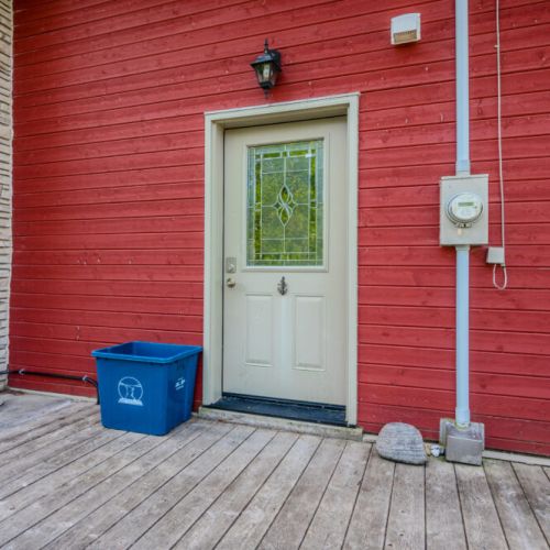 Discover the charm of this cozy cottage from the side, highlighting its rustic red exterior and direct access to outdoor adventures.