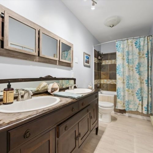 Additional full bathroom with double vanity and shower/tub combination.