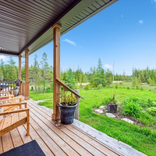 Wide steps lead you up to the entrance—flanked by porch lights, dual potted plants, and cozy Adirondack chairs. A space to relax and breathe.