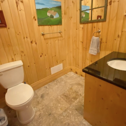 This charming powder room combines functionality with rustic style, featuring natural wood walls and a sleek granite countertop.