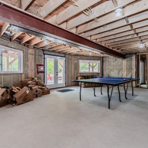 The unfinished basement offers a large space for recreational activities, including a table tennis table. The area is perfect for games and indoor fun!