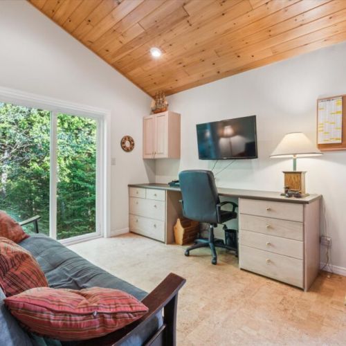 Work-from-retreat convenience: a private office with desk, chair, TV, and walk-out to the forest. Perfect for blending work with relaxation.