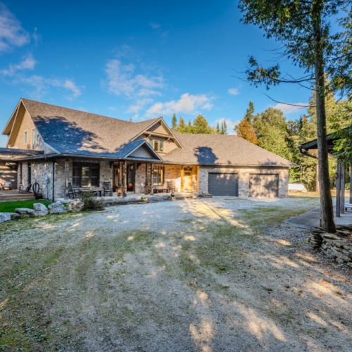 Beautiful stone home with a spacious driveway, and large garage—offering a serene retreat in a picturesque, wooded setting near the water.