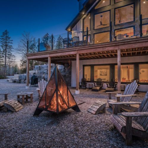 Unwind at this luxurious vacation rental with a stunning fire pit lounge, large glass windows, and upper-level deck—perfect for cozy evenings, group gatherings, and serene forest retreats.