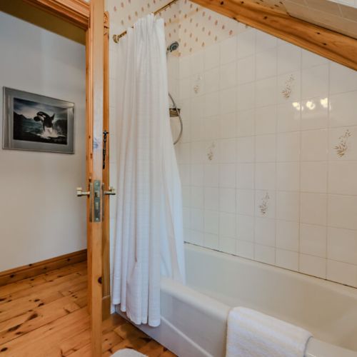 A charming bathroom featuring a classic bathtub with rustic wood details. The cozy design invites you to unwind and enjoy a serene bathing experience.