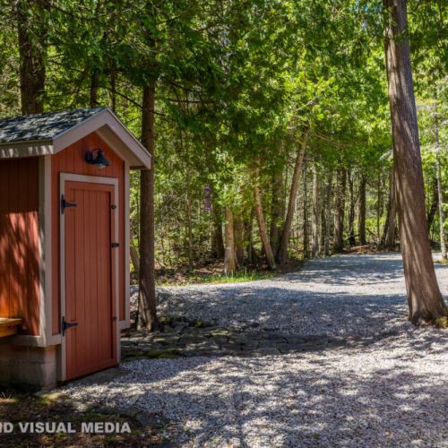 A peaceful woodland path leading to the cottage, with a charming pump house adding rustic character.