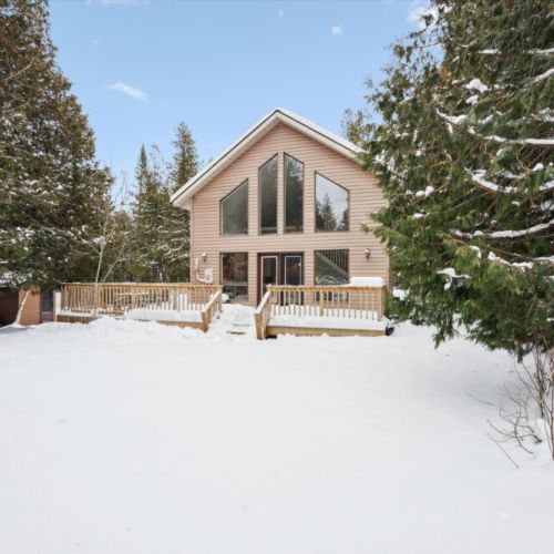 Private chalet-style exterior surrounded by snow-covered trees and natural beauty