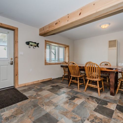 Share meals and laughter around the large wooden dining table, surrounded by windows that offer picturesque views and abundant natural light.