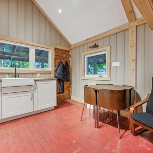 A practical space for sharing meals, hanging jackets, and coming and going from the covered deck just outside. The rustic wood tones and compact layout add to the cottage's charm.