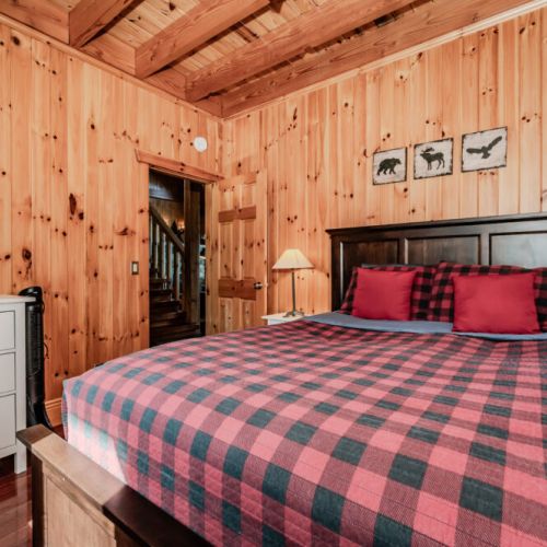 Spacious bedroom with red plaid bedding and cabin décor—perfect for couples enjoying a romantic getaway in the woods.