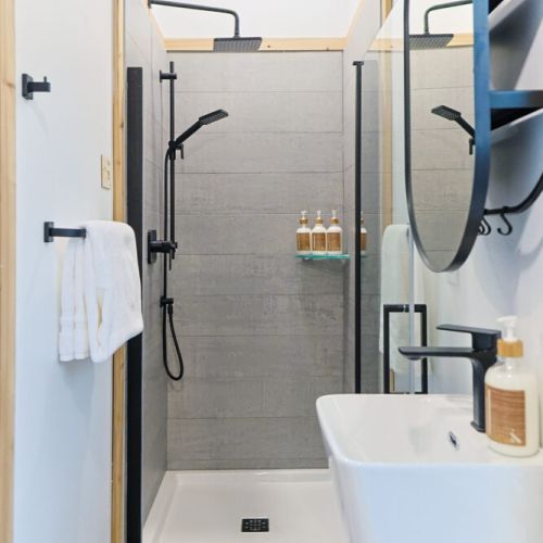 This sleek and modern bathroom features a walk-in shower with a rainfall shower head, perfect for refreshing after a day of exploring. The minimalist design and clean lines create a relaxing and spa-like atmosphere.