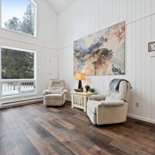 Relaxing seating area with plush chairs, tall windows, and abundant natural light