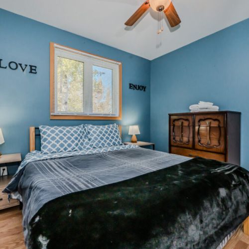 One of the three main-level bedrooms, featuring a comfortable bed, modern décor, and closet space.
