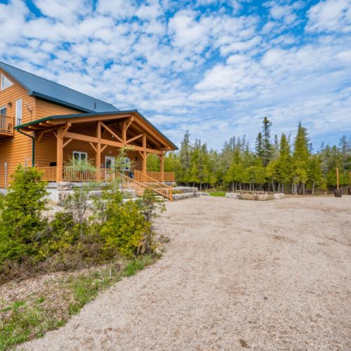 Saw N' LogzzZ showcases its impressive structure and beautifully landscaped front yard, offering a warm and inviting entrance.
