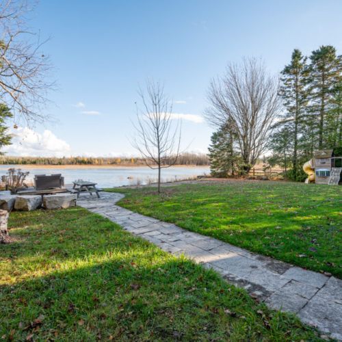 With a play structure for kids and a wooden dock for adults, the backyard transforms into a versatile waterside resort, catering to the diverse interests of every member of the family. It's a space where joyful laughter and peaceful moments coexist in harmony.